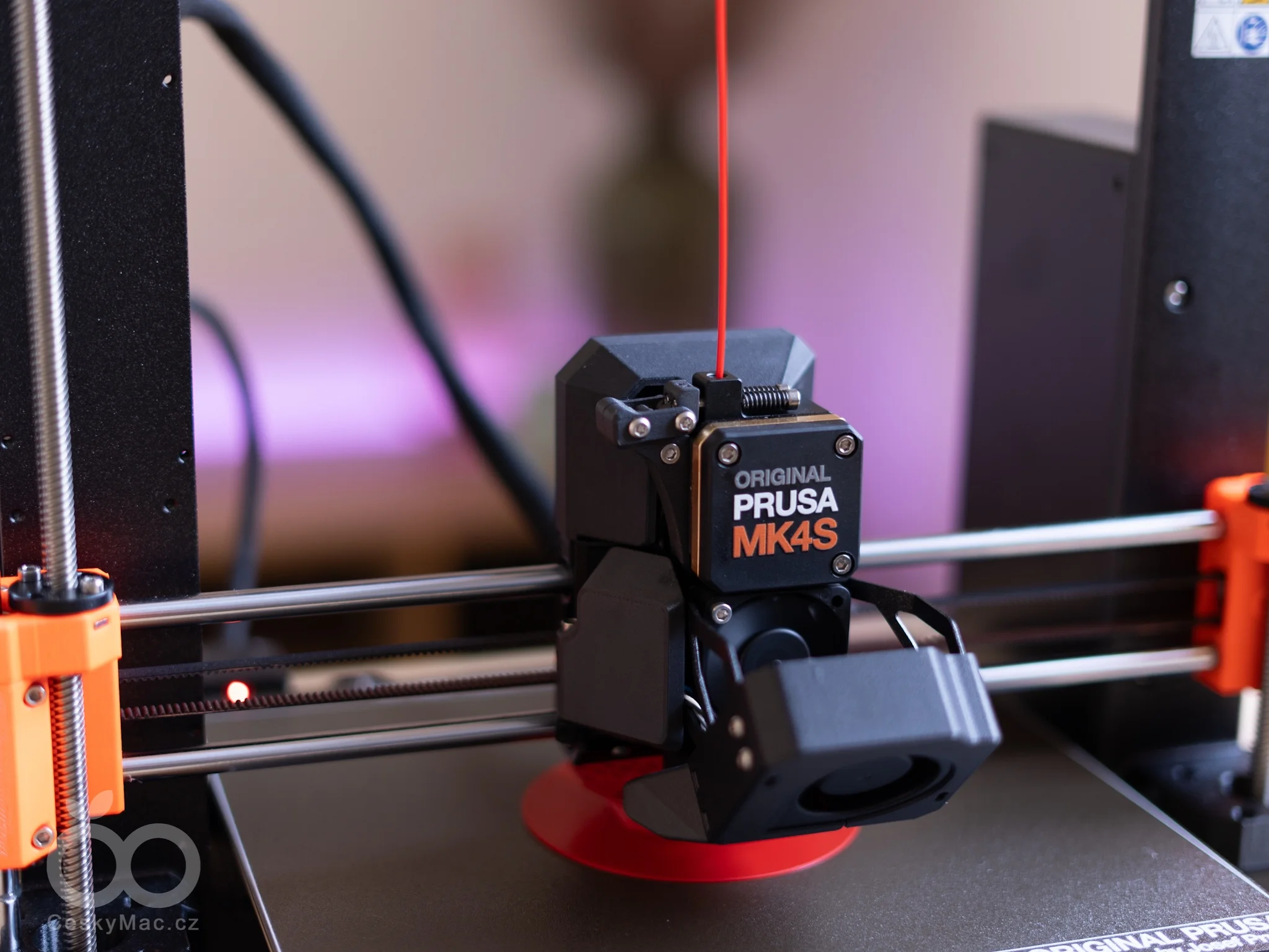 Detail tiskové hlavy 3D tiskárny Original Prusa MK4S s červeným filamentem